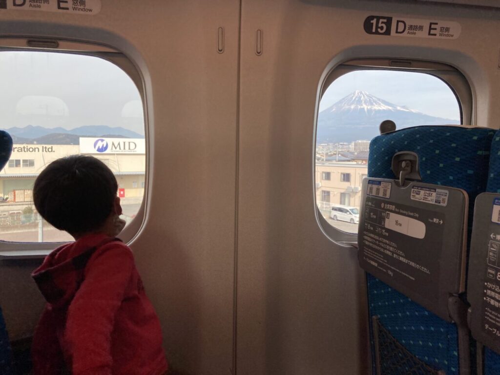 新幹線の車窓からの景色を楽しむ子供